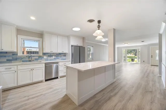 a large kitchen with a center island wooden floor stainless steel appliances and cabinets