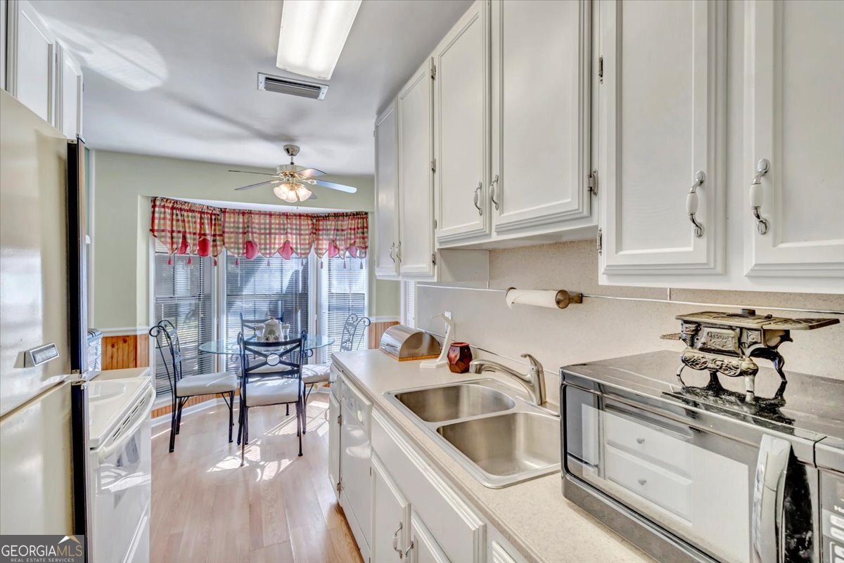 1702 Vada Road Bainbridge, GA 39817 - Photo 17 of 33 a kitchen with stainless steel appliances granite countertop a sink dishwasher a stove and white cabinets with wooden floor