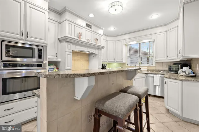 a kitchen with stainless steel appliances granite countertop a sink and dishwasher with white cabinets