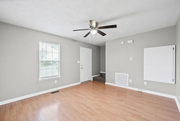 a view of empty room with wooden floor and ceiling fan