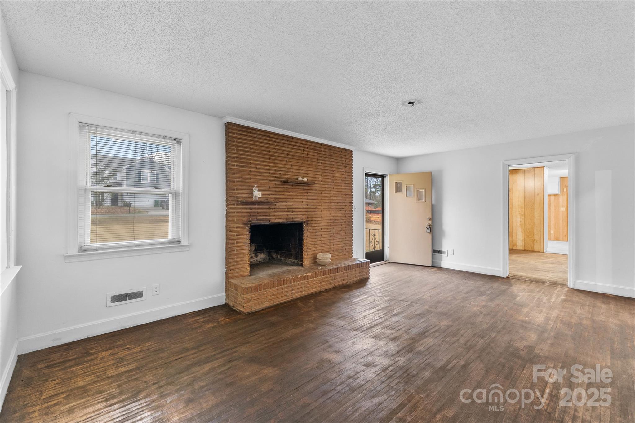 a view of an empty room with a fireplace and a window