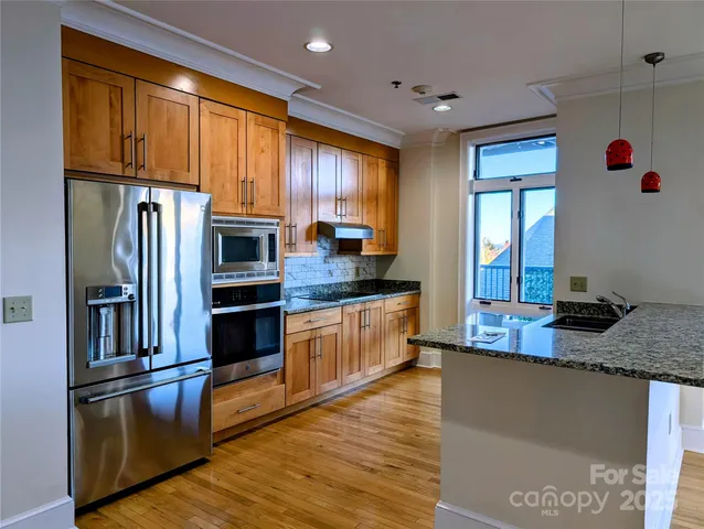 a kitchen with stainless steel appliances granite countertop a refrigerator a stove and a sink