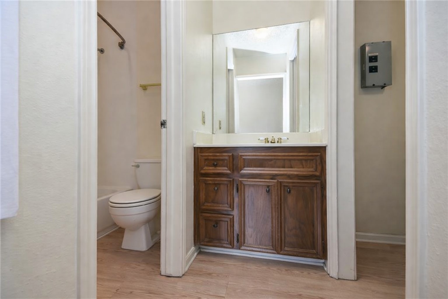 3115 Tom Green Street, Unit 404 Austin, TX 78705 - Photo 7 of 19 Bathroom featuring a wood-finish vanity with a light-toned countertop, a rectangular mirror, and a toilet with a shower/tub combination