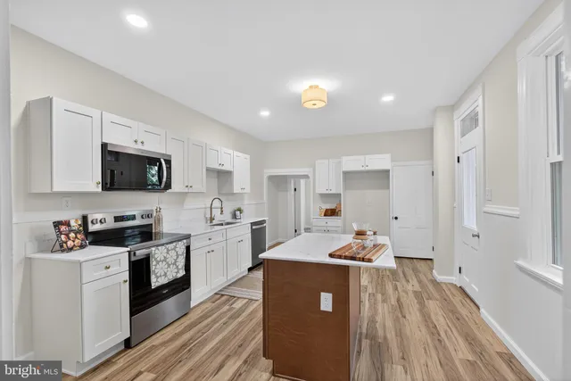 a open kitchen with cabinets a sink dishwasher and a stove with wooden floor