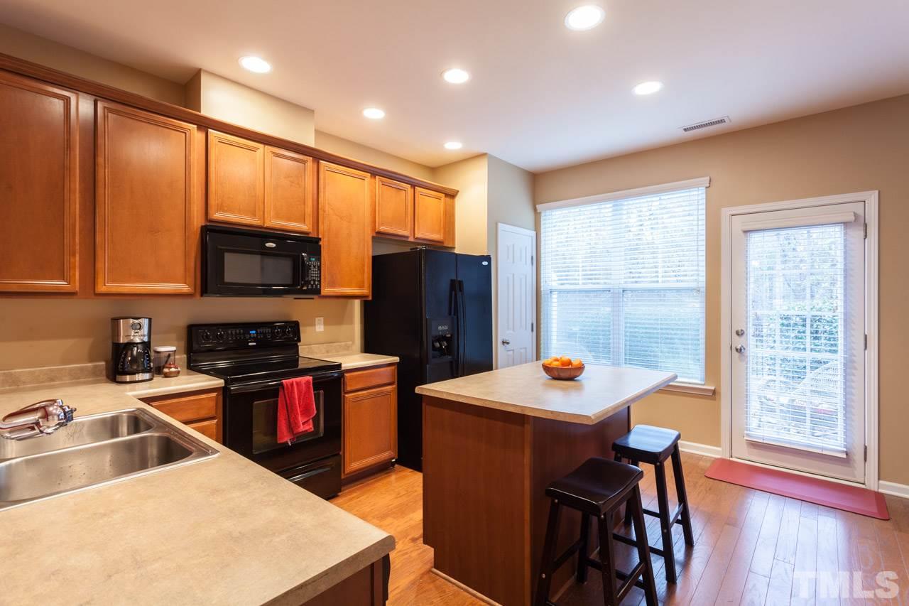 2930 Casona Way Raleigh, NC 27616 - Photo 6 of 25 a kitchen with stainless steel appliances granite countertop a refrigerator a sink dishwasher a stove and a dining table with wooden floor