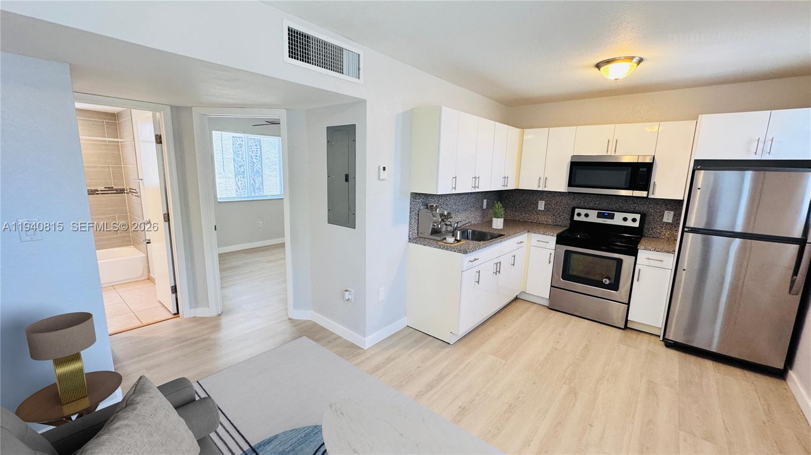 1737 Northwest 3rd Avenue, Unit 7 Miami, FL 33136 - Photo 3 of 9 a kitchen with white cabinets a sink and wooden floor