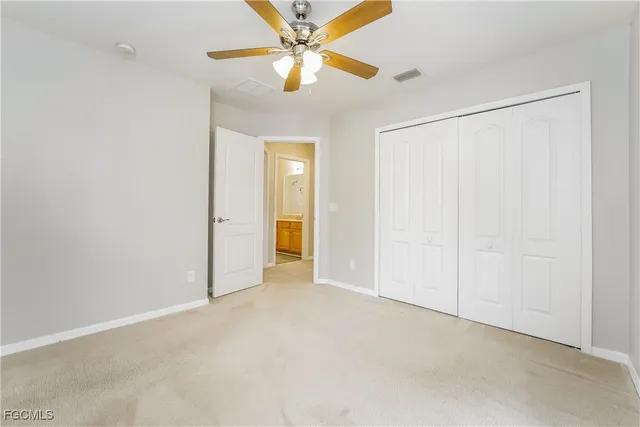 an empty room with closet and a ceiling fan