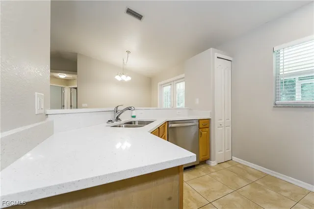 a view of a kitchen with a sink and dishwasher with chairs