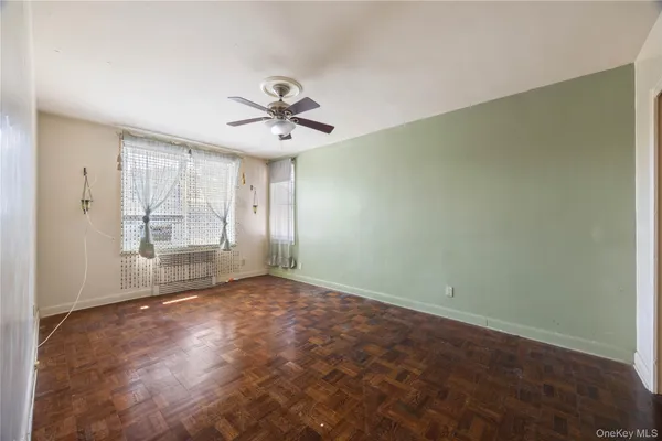 an empty room with windows and chandelier fan
