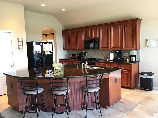 a kitchen with granite countertop a sink cabinets and stainless steel appliances