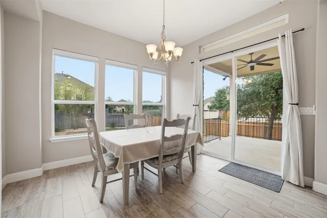 a kitchen with stainless steel appliances a dining table chairs refrigerator and microwave