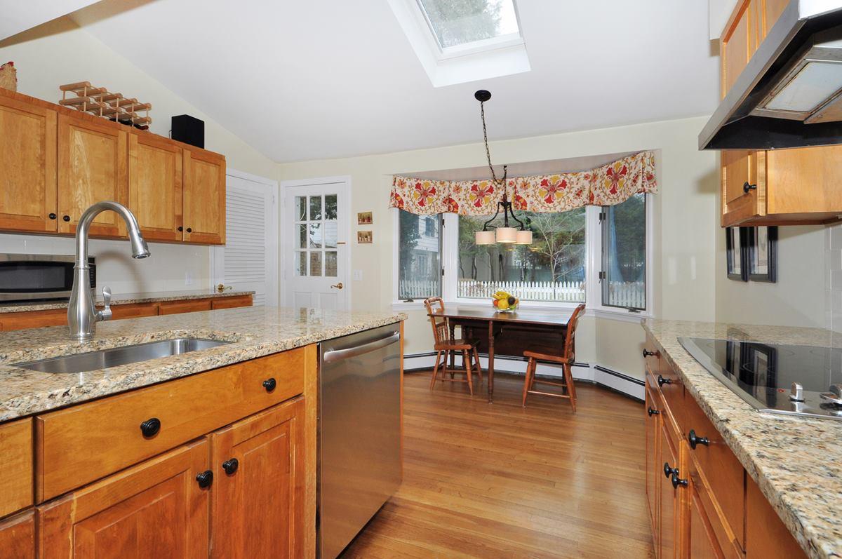 112 Hollow Tree Ridge Road Darien, CT 06820 - Photo 10 of 27 a large kitchen with granite countertop a stove a sink a dining table and chairs with wooden floor