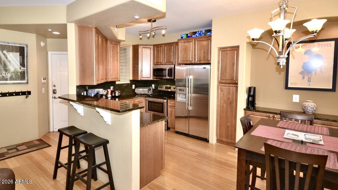 5303 North 7th Street, Unit 117 Phoenix, AZ 85014 - Photo 3 of 31 a kitchen with a refrigerator a stove and a dining table with wooden floor