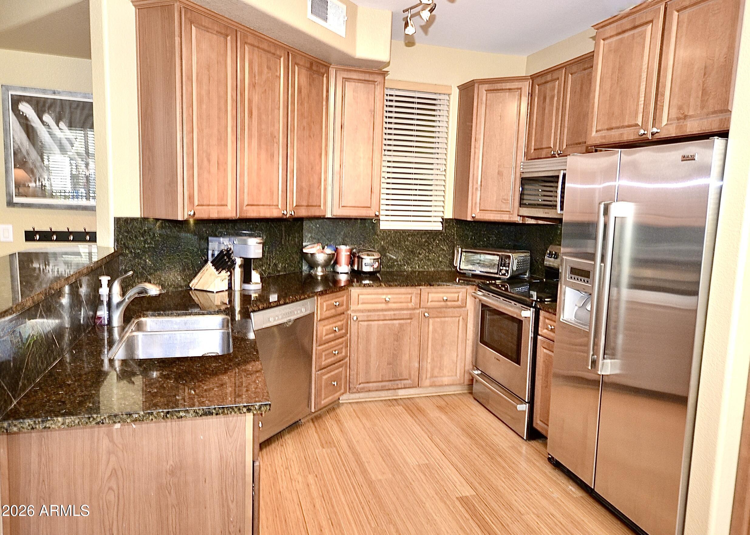 5303 North 7th Street, Unit 117 Phoenix, AZ 85014 - Photo 4 of 31 a kitchen with granite countertop a refrigerator a sink dishwasher stove and white cabinets with wooden floor