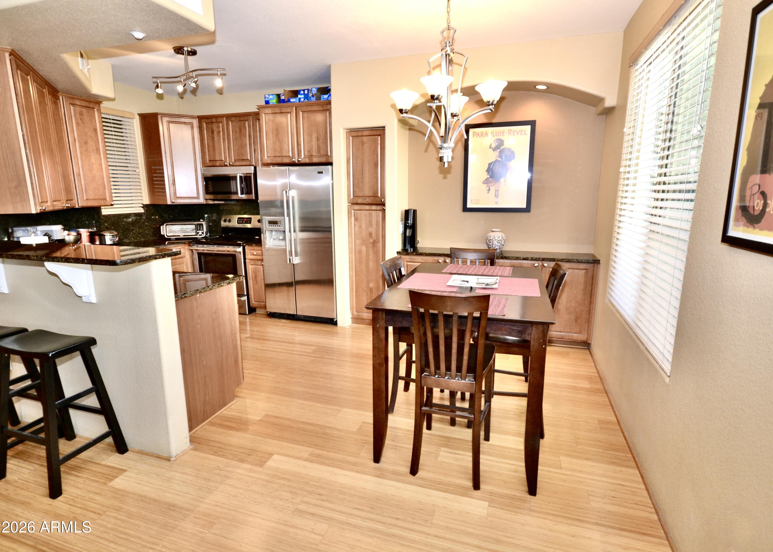 5303 North 7th Street, Unit 117 Phoenix, AZ 85014 - Photo 6 of 31 a kitchen with stainless steel appliances wooden floor dining table and chairs
