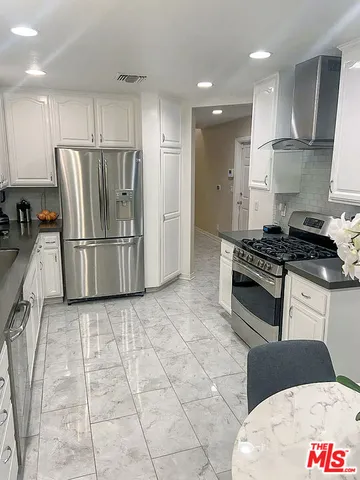 a kitchen with granite countertop a refrigerator and a stove top oven