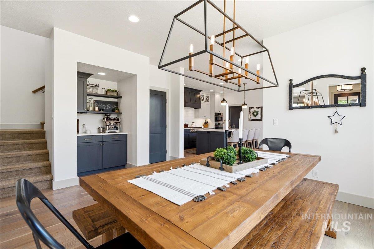 3794 South Single Tree Avenue Boise, ID 83716 - Photo 16 of 50 Dining area featuring a substantial wood-finish table with a matching bench, a striking geometric chandelier, and light wood-finish flooring