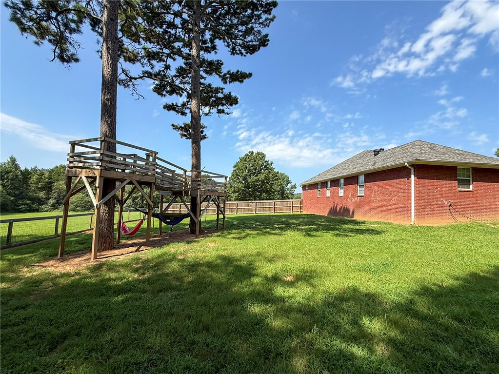 70 Walthall Road Russellville, AR 72802 - Photo 46 of 51 Expansive green lawn with a custom-built treehouse structure, mature trees, and a red brick exterior