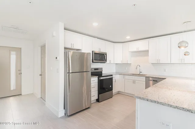 a kitchen with granite countertop stainless steel appliances a refrigerator a stove top oven and sink