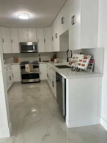 a kitchen with stainless steel appliances a refrigerator sink and white cabinets