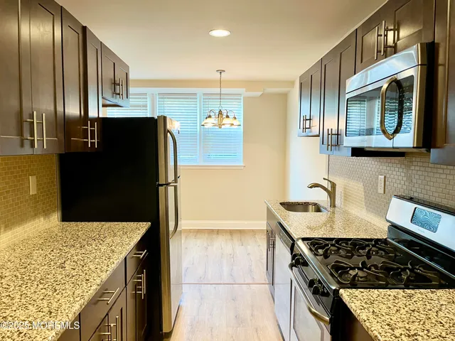 a kitchen with stainless steel appliances granite countertop a stove a refrigerator and a microwave