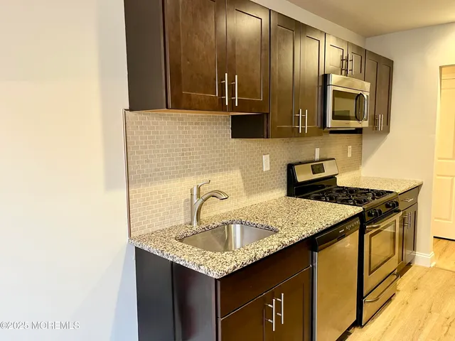 a kitchen with stainless steel appliances granite countertop a sink stove and microwave