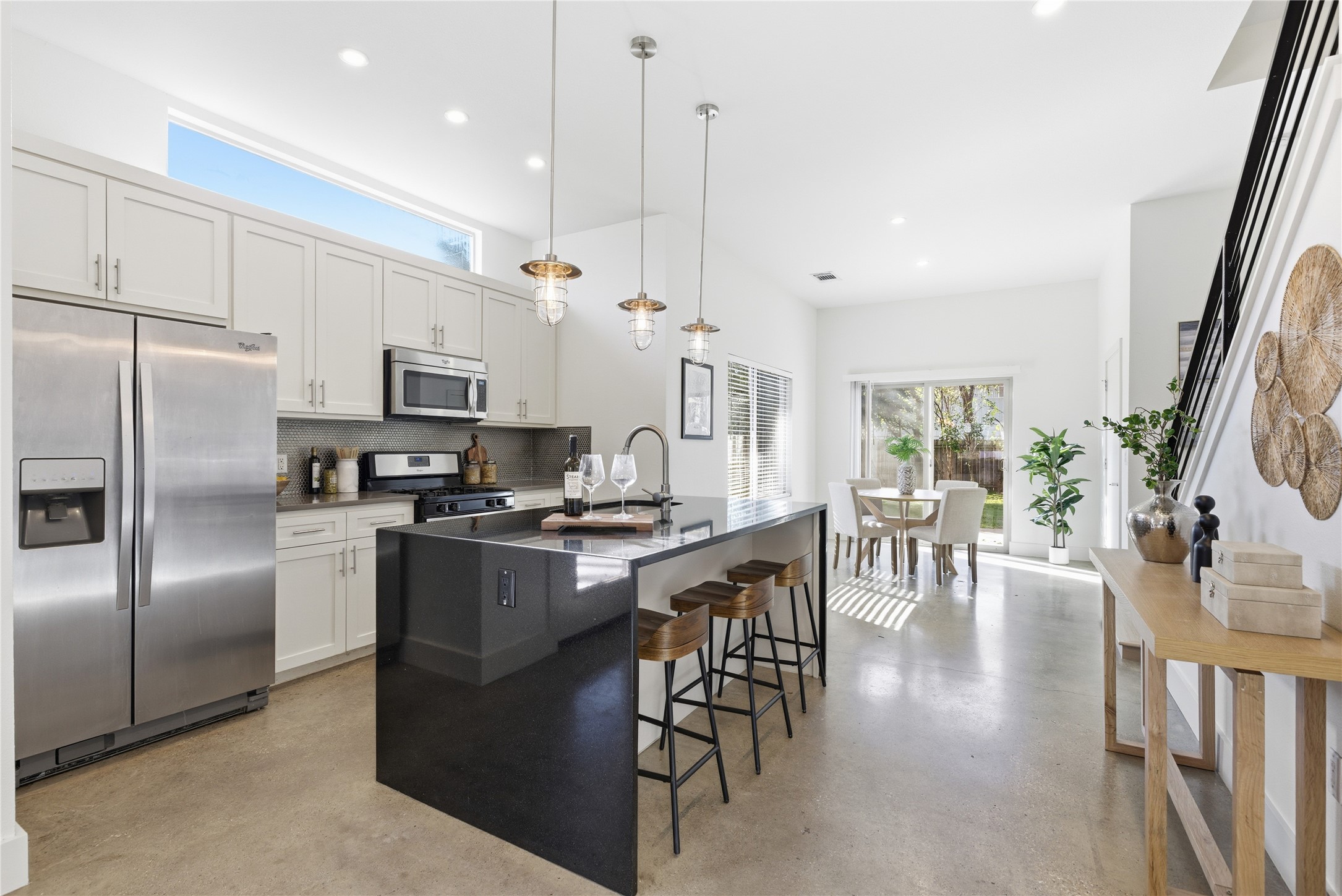 701 Zennia Street, Unit B Austin, TX 78751 - Photo 11 of 40 Kitchen featuring stainless steel appliances, an island with sink, decorative light fixtures, a kitchen breakfast bar, and concrete flooring
