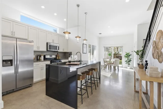 a kitchen with stainless steel appliances granite countertop a refrigerator a stove and a sink