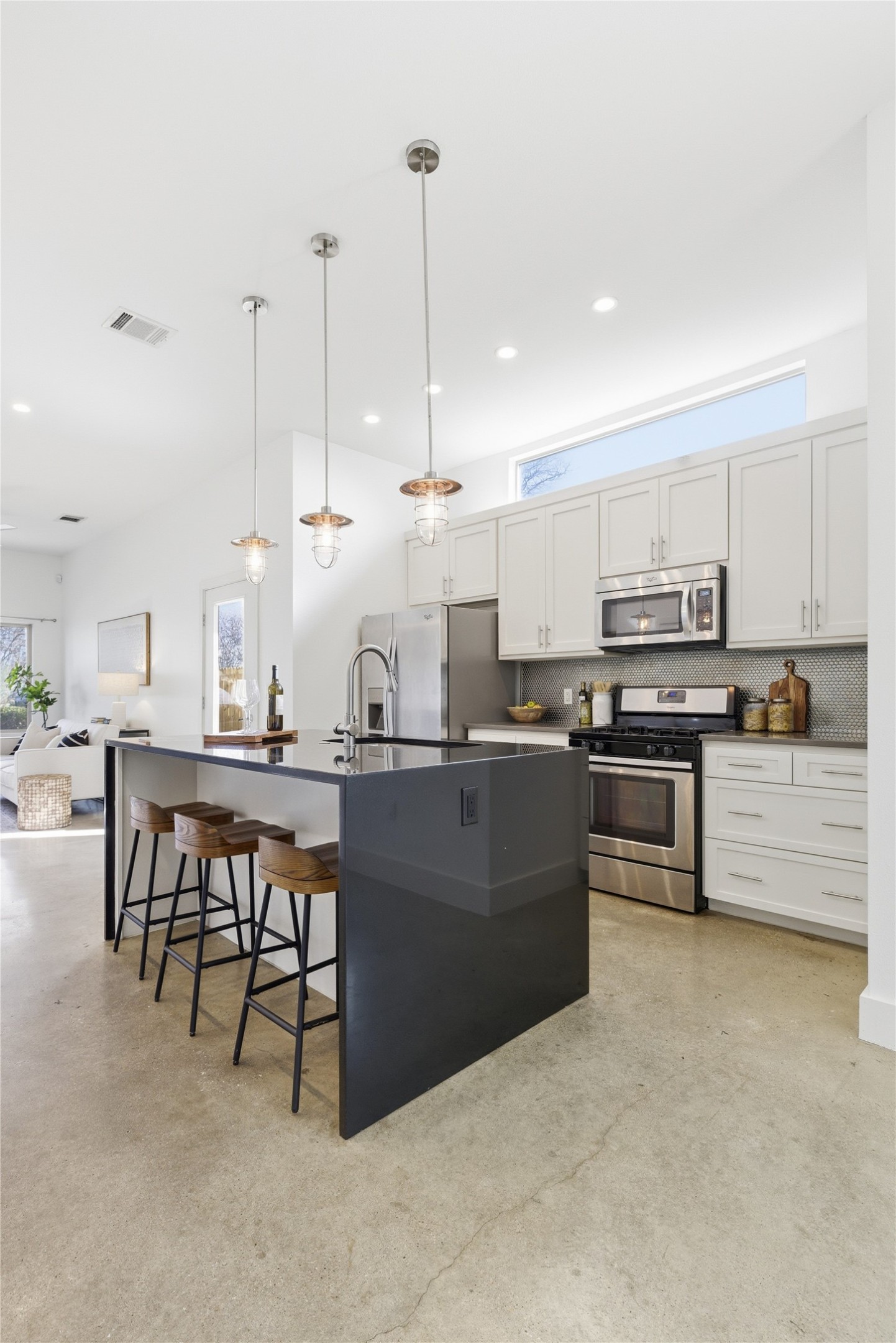 701 Zennia Street, Unit B Austin, TX 78751 - Photo 19 of 40 Kitchen featuring decorative light fixtures, a kitchen bar, white cabinetry, appliances with stainless steel finishes, and a spacious island