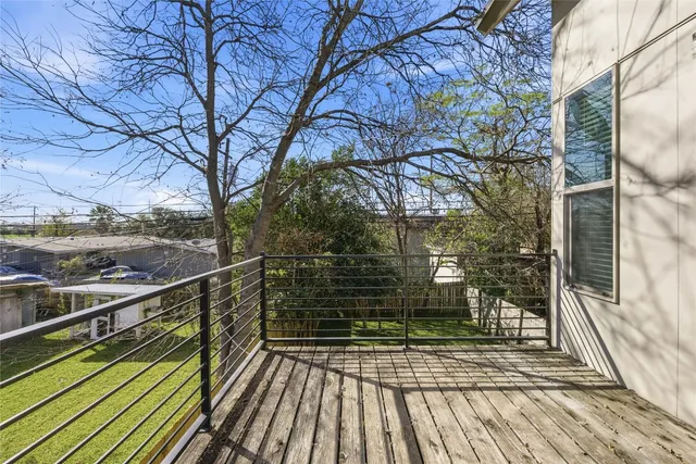 a view of a balcony with wooden floor and large trees