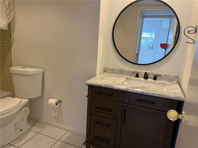 a bathroom with a granite countertop toilet a sink and mirror
