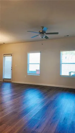 an empty room with wooden floor chandelier fan and windows