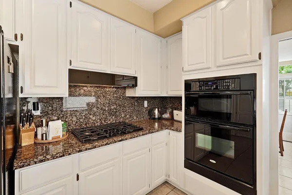 a kitchen with granite countertop white cabinets and stainless steel appliances