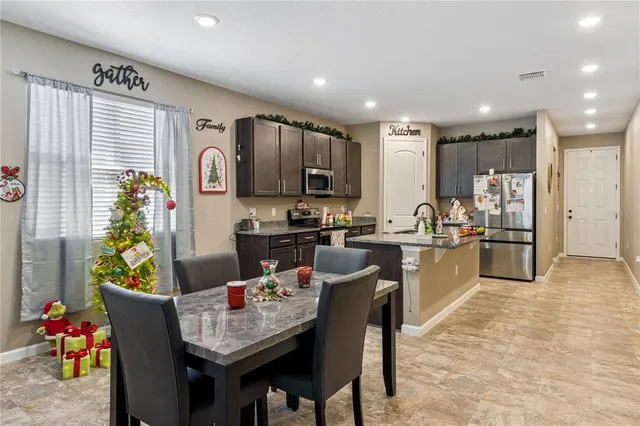 a kitchen with kitchen island granite countertop a stove top oven a sink a dining table and chairs