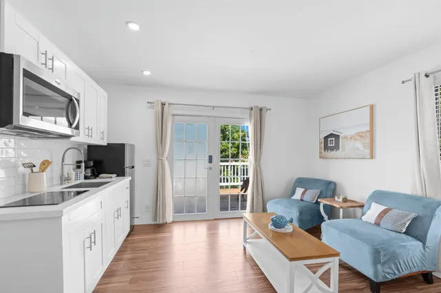 a living room with stainless steel appliances furniture a rug and a kitchen view