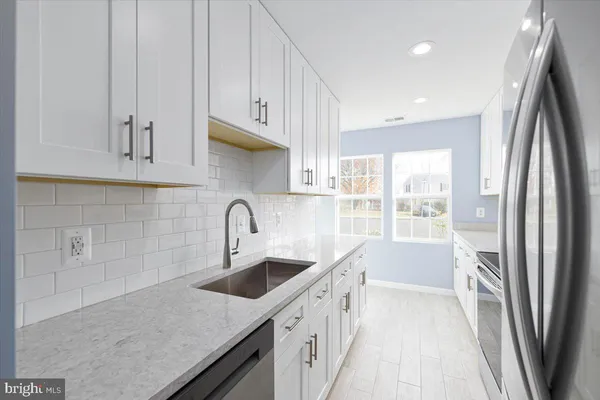 a kitchen with stainless steel appliances granite countertop a sink a refrigerator and a granite counter tops