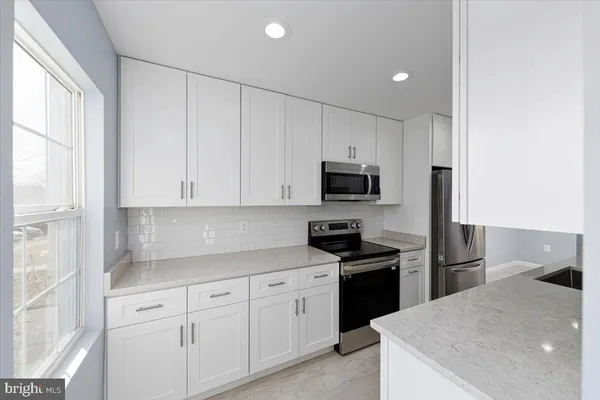a kitchen with white cabinets and stainless steel appliances