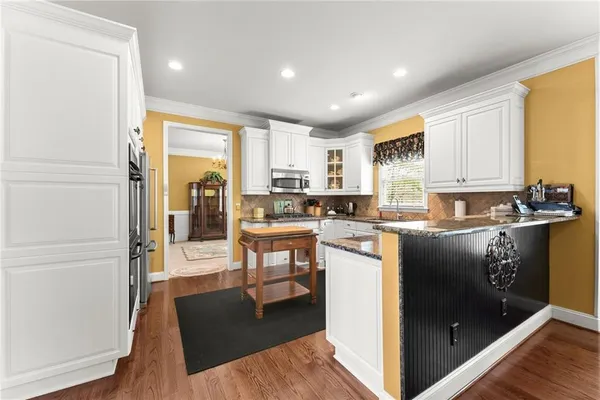 a kitchen with granite countertop a refrigerator a sink a stove top oven a dining table and chairs