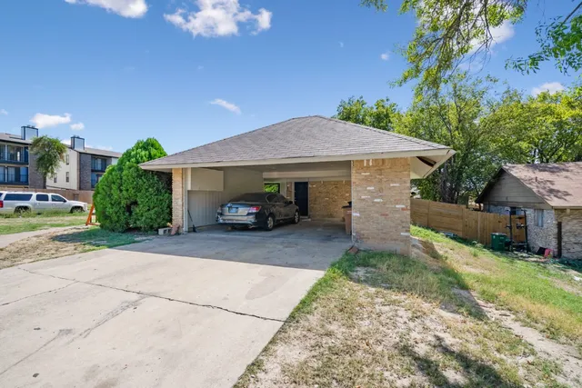 a view of a car parked in front of a brick house with plants