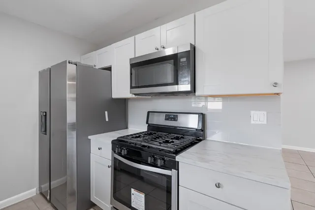 a kitchen with stainless steel appliances white cabinets and a stove top oven
