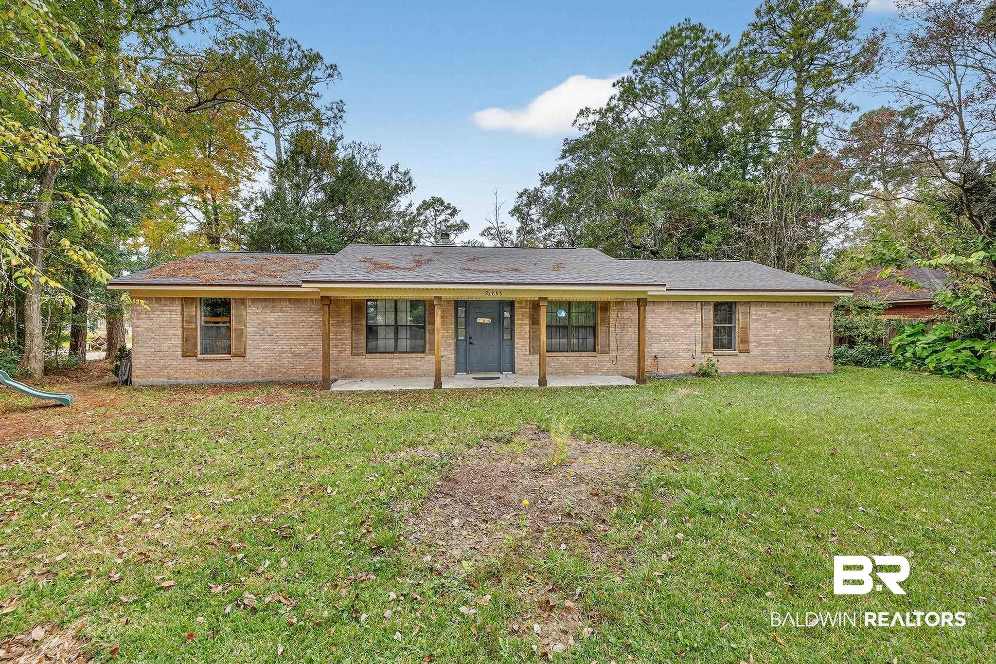 Front of property featuring brick siding, a lawn, and a porch