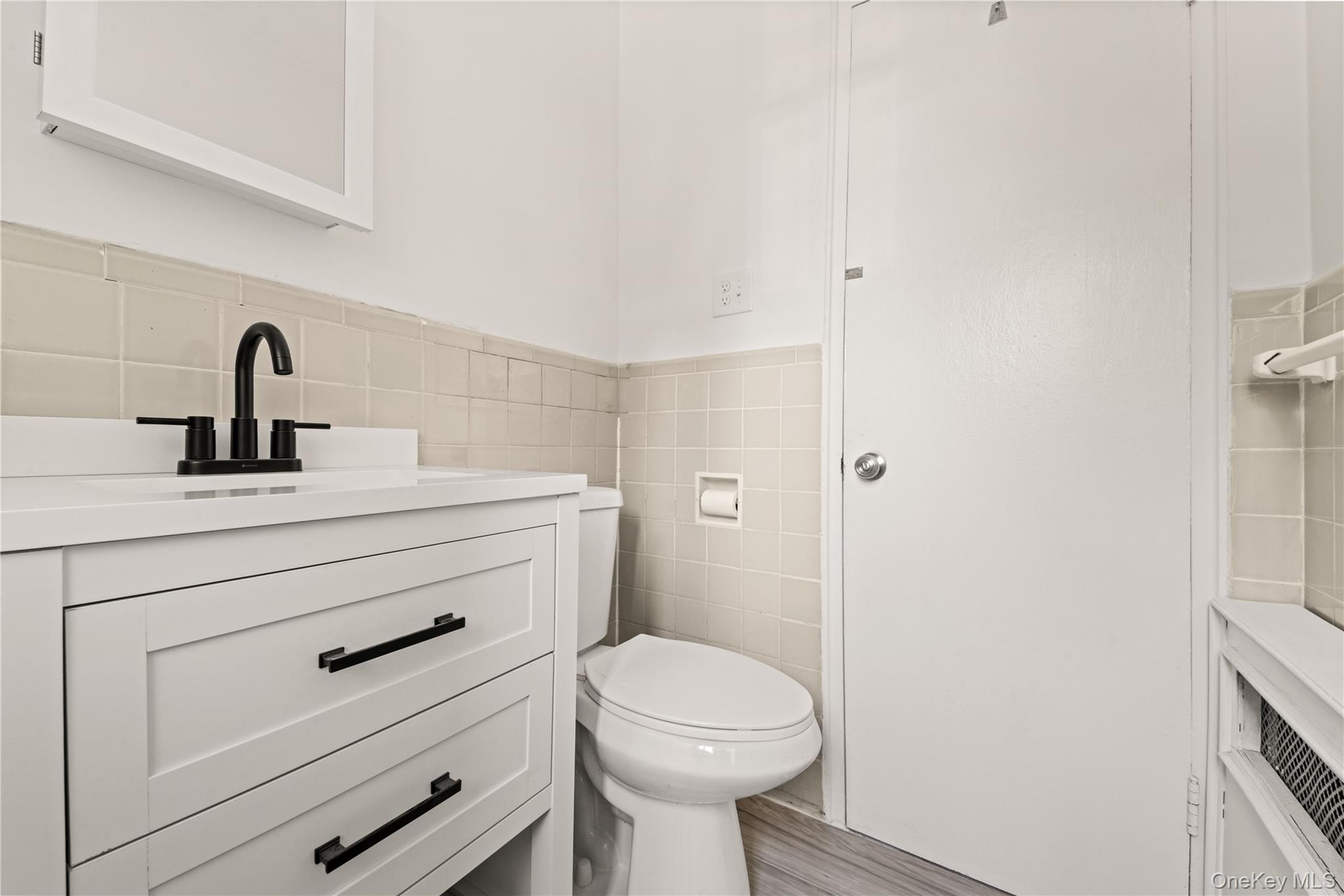 224-17 Manor Road, Unit 1 Queens, NY 11427 - Photo 14 of 16 Half bathroom featuring tile walls, a wainscoted wall, vanity, and wood finished floors