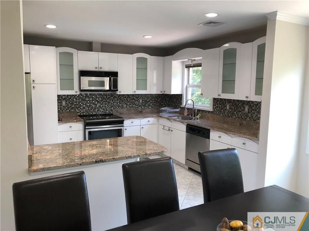 144 Kimberly Road Colonia, NJ 07067 - Photo 11 of 27 a kitchen with stainless steel appliances granite countertop a sink a stove a microwave a counter top and cabinets