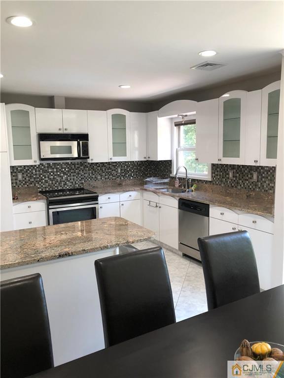 144 Kimberly Road Colonia, NJ 07067 - Photo 7 of 27 a kitchen with stainless steel appliances granite countertop a sink a stove top oven a counter space and cabinets