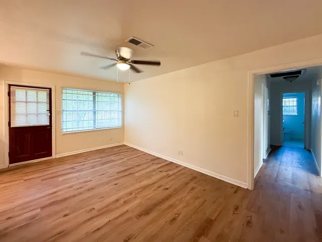 a view of empty room with wooden floor and fan