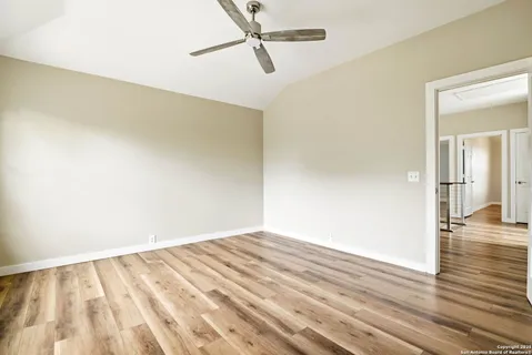 a view of empty room with wooden floor and fan
