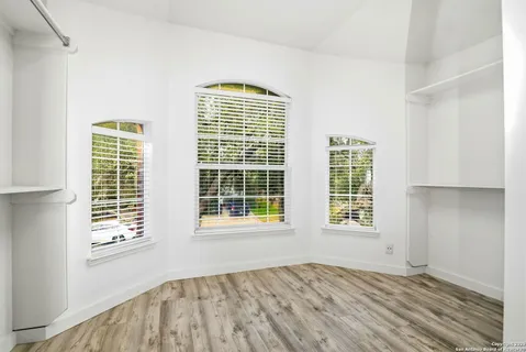a view of an empty room with a window and wooden floor