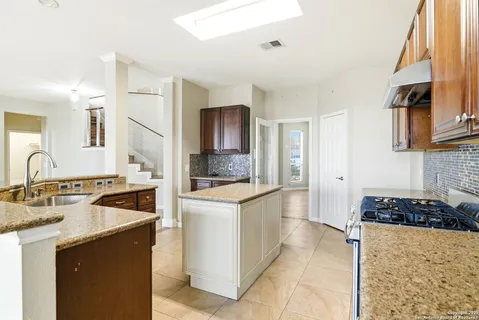 a kitchen with granite countertop a sink stove and refrigerator