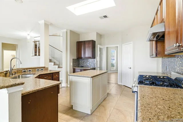 a kitchen with granite countertop a sink stove and refrigerator