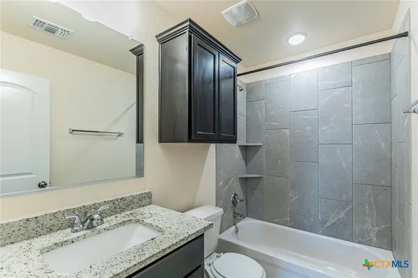 a bathroom with a granite countertop sink toilet and shower
